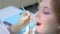 Dentist orthodontist examines girl`s teeth using dental tools needle and mirror.