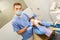 Dentist performing teeth treatment with scared female patient