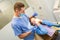 Dentist performing teeth treatment with scared female patient