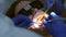 Dentist is preparing woman's teeth for installing ceramic veneers using a drill.