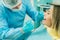 A dentist in a protective mask sits next to him and treats a patient in the dental office