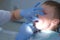 Dentist rinses boy& x27;s mouth water holding saliva ejector during hygiene cleaning.