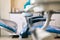 Dentist`s chair, side view, blue with white background and instrument table