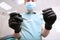 Dentist`s hands in black latex gloves with medical instruments . Face out of focus. POV. Copy space