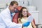 Dentist showing mirror to young patient in dental clinic