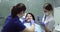 Dentist starting the work on the patient using a mirror , dental nurse sits beside