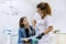 Dentist talking to woman patient in dental chair. Female doctor with x-ray takes diagnosis and recommends treatment