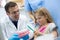 Dentist teaches girl properly brushing on model of teeth