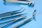 Dentist tools on blue glass table: dental mirror, kornzange, explorer, forceps and dental forceps for pulling teeth. Dental