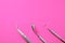 Dentist tools: mirror, dental probe and tweezers on pink gradient background