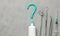 Dentist tools and toothpaste in the shape of a question mark. Mirror, hook, tweezers and syringe tools. Concept of how to choose a