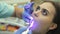 Dentist using dental curing UV lamp on teeth of patient