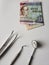 dentist utensils for oral review and jamaican banknote of 50 dollars