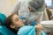 Dentist woman doing teeth checkup of little girl looking with fear sitting in a dental chair in clinic