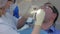 Dentist woman installing retractor into man`s mouth in stomatology clinic.
