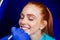 Dentist works on tooth crown in dental laboratory ultraviolet painting teeth with mineral and calcium cream to young red