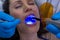 Dentists examining female patient with dental curing light