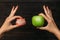 Denture and Apple in the hands of a doctor. False teeth denture against green granny smith apple. Dental prosthesis care. Dental