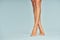 Depilation concept. Cropped shot of beautiful female legs with soft silky skin over blue background