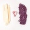 Depilatory Purple Pearl Hard Wax Beans, wooden stick spatula, heart, concept of skincare bodycare, beauty industry, spa salon,