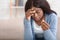 Depressed afro woman holding gold wedding ring, sad about divorce