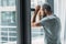 depressed bearded man leaning at window and looking through