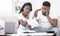 Depressed black couple looking at invoice at home, upset about bills