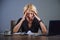 Depressed business woman working overwhelmed at office with laptop computer feeling exhausted suffering headache holding her head