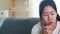 Depressed crying Asian business woman stressed with headache sitting on sofa in living room at house.