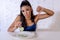 Depressed dieting woman holding folk looking at small green vegetable on empty plate