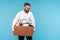 Depressed fired male employee crying hiding face, leaving office workplace with prepared box of belongings