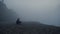 Depressed guy sitting sea beach in foggy morning. Worried man touching sand