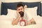 Depressed man in bed. time management. tired bearded man hipster with alarm clock. brutal sleepy man in bedroom. mature