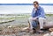 Depressed man sitting on driftwood on beach