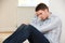 Depressed Man Sitting On Floor Of Empty Room