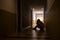 Depressed man sitting on the floor with his head down, silhouette of stressed young man holding his head in the hallway