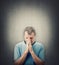 Depressed middle aged man praying over grey wall background with copy space above head. Senior male desperate looking down, keeps