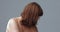 Depressed naked woman lowered her head, covering her face with hair. Pensive red-haired woman on gray background. Aging