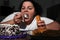Depressed overweight woman eating sweets in kitchen