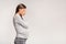 Depressed Pregnant Woman Covering Face Standing Over Gray Background