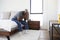 Depressed Senior Man Looking Unhappy Sitting On Side Of Bed At Home With Head In Hands