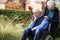 Depressed Senior Man In Wheelchair Being Pushed By Wif