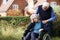 Depressed Senior Woman In Wheelchair Being Pushed By Husband