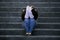 Depressed student woman or bullied teenager girl sitting outdoors on street staircase scared and anxious victim of bullying