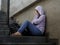 Depressed student woman or bullied teenager girl sitting outdoors on street staircase scared and anxious victim of bullying