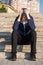 Depressed teenage boy holding his head with his hands sitting on stairs outdoors. Teen depression concept