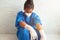 A depressed and tired African-American nurse wears a mask and gloves on the hospital floor