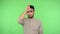 Depressed upset brunette man showing loser gesture and looking at camera with dismal expression. green background, chroma key