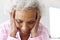 Depressed Woman Looking Unhappy Sitting On Side Of Bed At Home With Head In Hands