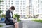 Depressed woman in medical mask sits on parapet outdoors with a box of personal items from the desktop. Unemployed girl